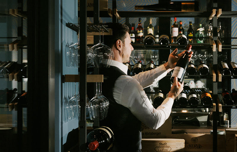 Ein Barkeeper w&auml;hlt einen exklusiven Wein im begehbaren Weinraum.